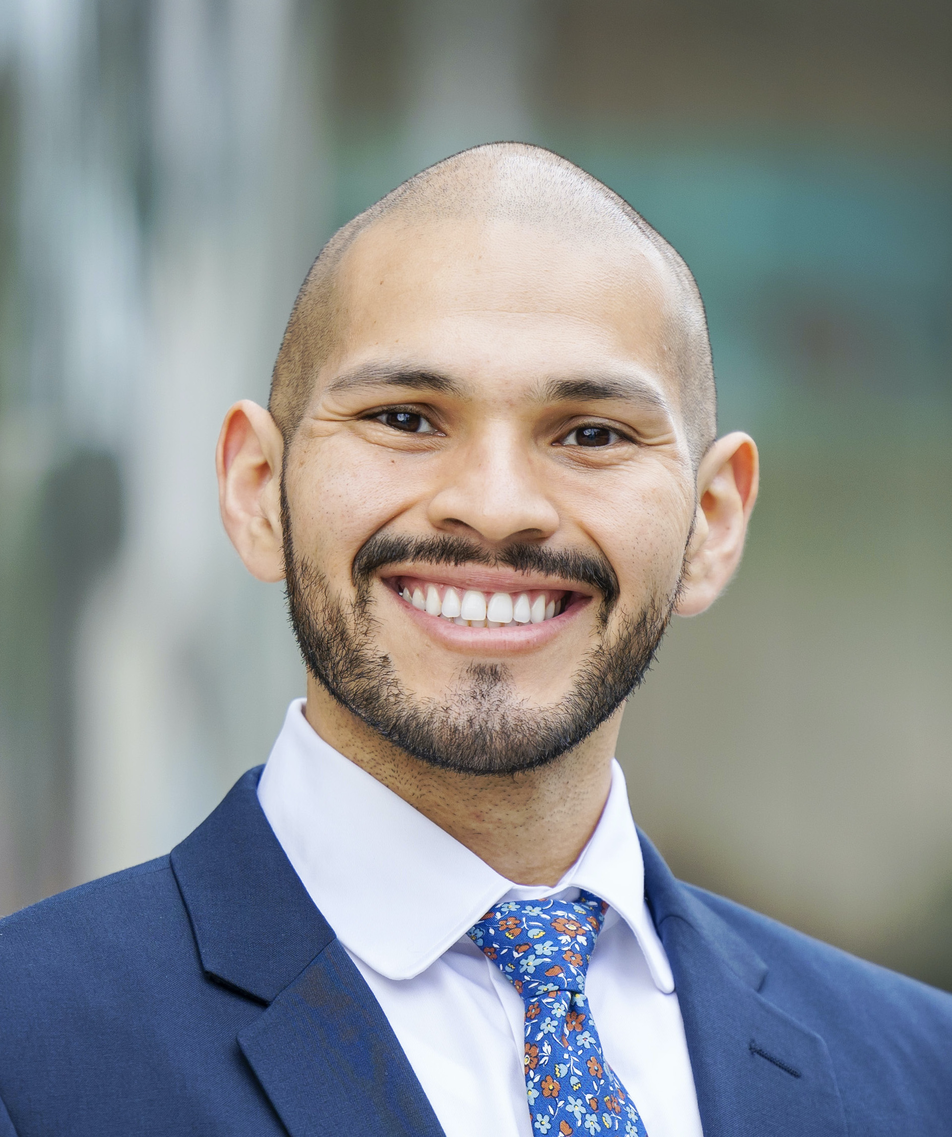 Headshot of a man smiling wearing a suit and tie.